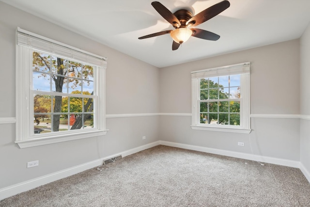 carpeted empty room with visible vents, ceiling fan, and baseboards