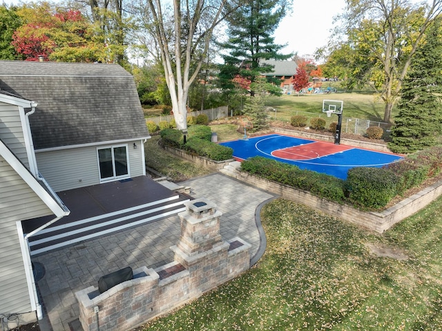 view of sport court with basketball hoop, fence, and a yard