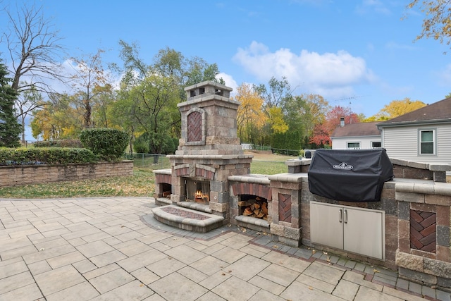 view of patio / terrace with an outdoor stone fireplace, a grill, and fence