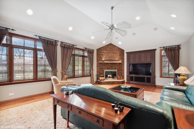 living room featuring ceiling fan, light wood-type flooring, a brick fireplace, and vaulted ceiling