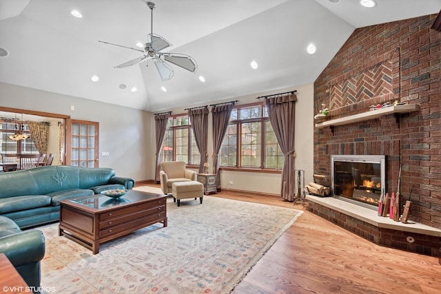 living room featuring a brick fireplace, high vaulted ceiling, ceiling fan, and light hardwood / wood-style flooring