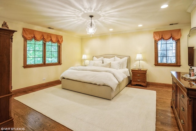 bedroom with a chandelier, ornamental molding, and hardwood / wood-style flooring