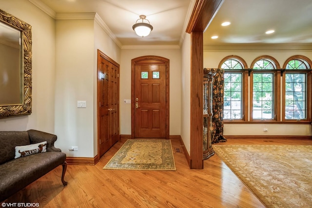 entryway with light wood-type flooring and crown molding