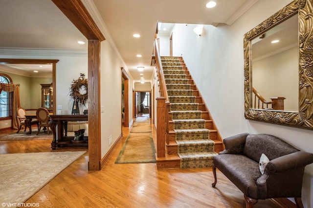 stairway with crown molding and wood-type flooring