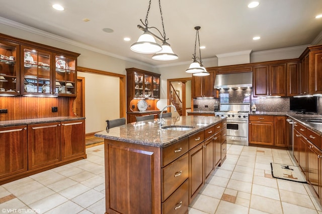 kitchen featuring pendant lighting, a center island with sink, wall chimney range hood, appliances with stainless steel finishes, and sink