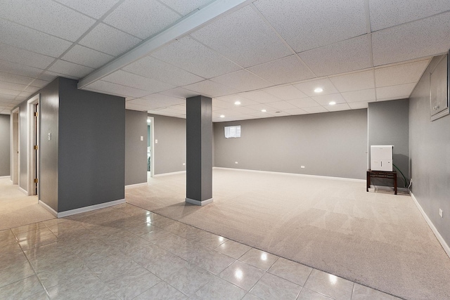 basement featuring a paneled ceiling and light tile patterned flooring