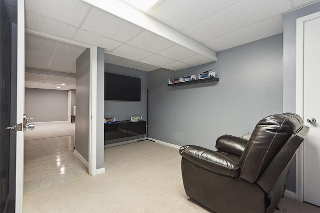 sitting room featuring a drop ceiling and carpet