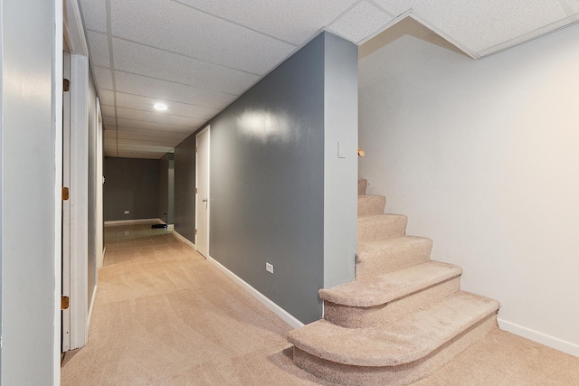 hall with carpet floors and a paneled ceiling