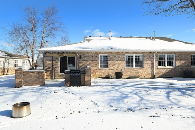 snow covered rear of property featuring central air condition unit