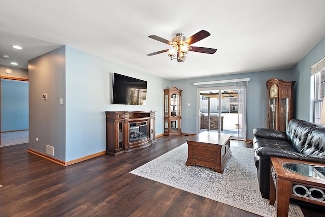 living room with a healthy amount of sunlight, ceiling fan, dark hardwood / wood-style floors, and a fireplace