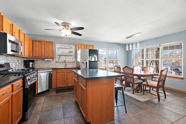 kitchen with sink, a kitchen island, a healthy amount of sunlight, and appliances with stainless steel finishes