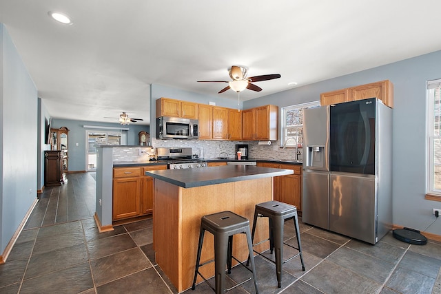 kitchen with a kitchen island, stainless steel appliances, a breakfast bar, and a healthy amount of sunlight