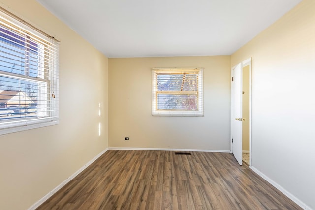 empty room with a healthy amount of sunlight and dark hardwood / wood-style floors