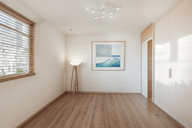 spare room featuring light hardwood / wood-style floors and a notable chandelier