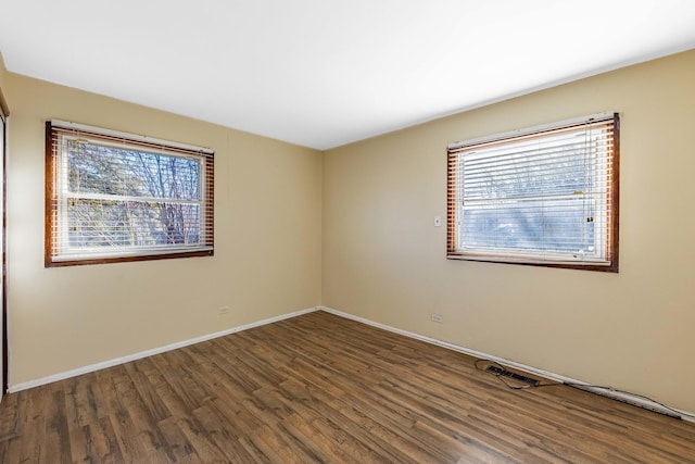 empty room with a healthy amount of sunlight and dark hardwood / wood-style flooring