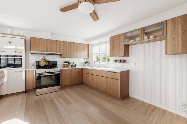 kitchen featuring sink, stainless steel gas stove, light hardwood / wood-style flooring, and range hood