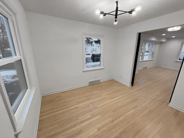 empty room featuring light hardwood / wood-style flooring and a chandelier