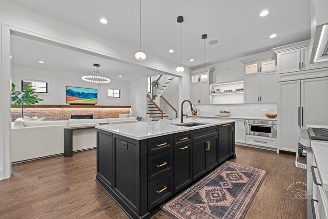 328 S Loomis St, Naperville, IL 60540 - kitchen featuring dark cabinetry, white cabinetry, oven, a kitchen island with sink, and decorative light fixtures
