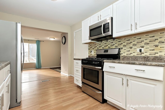 kitchen with backsplash, white cabinetry, light wood-type flooring, and appliances with stainless steel finishes