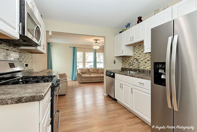 kitchen featuring decorative backsplash, appliances with stainless steel finishes, white cabinetry, and sink