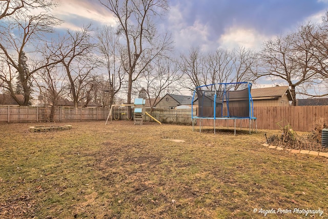 yard at dusk with a playground and a trampoline