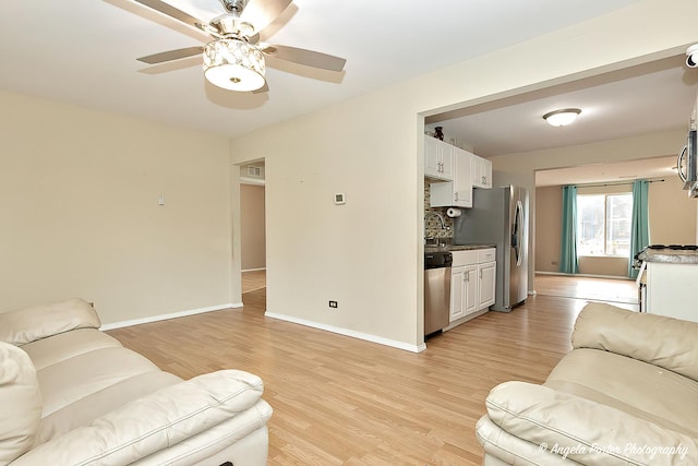 living room with light hardwood / wood-style floors, ceiling fan, and sink