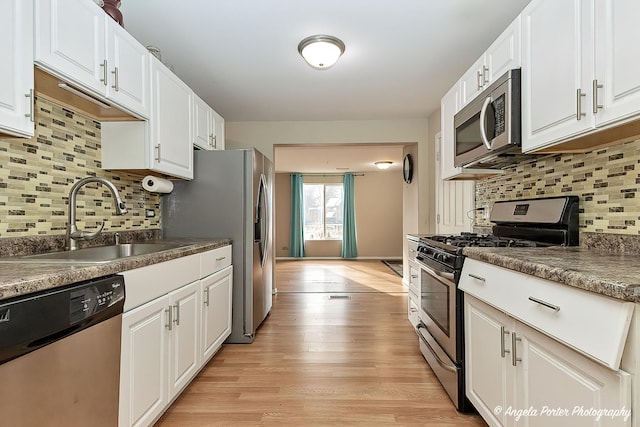 kitchen with decorative backsplash, sink, white cabinets, and appliances with stainless steel finishes