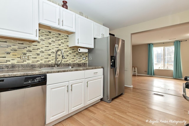 kitchen featuring decorative backsplash, white cabinetry, sink, and appliances with stainless steel finishes