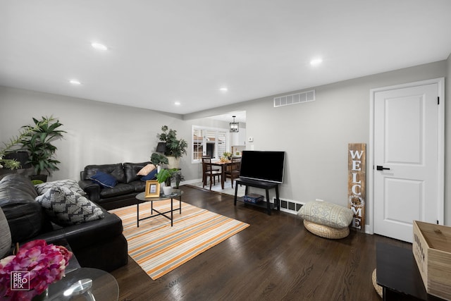 living room featuring a chandelier and dark wood-type flooring