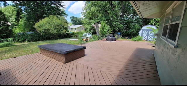 wooden terrace featuring a lawn, a hot tub, and a storage shed