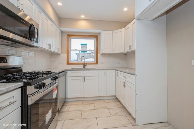 kitchen with light stone countertops, tasteful backsplash, white cabinetry, sink, and stainless steel appliances