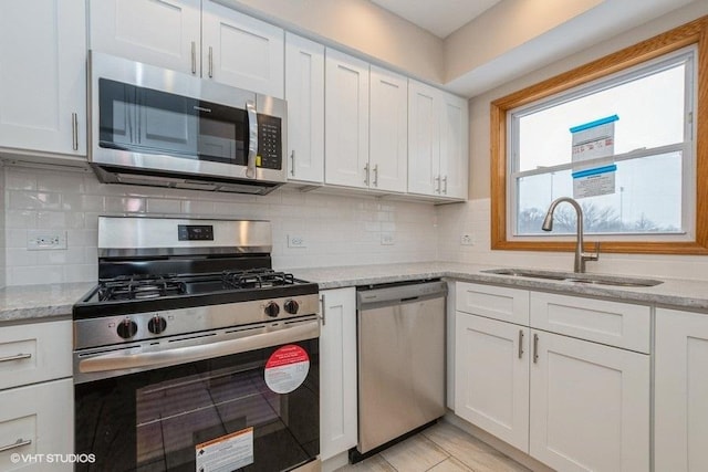 kitchen with light stone countertops, decorative backsplash, sink, white cabinets, and stainless steel appliances