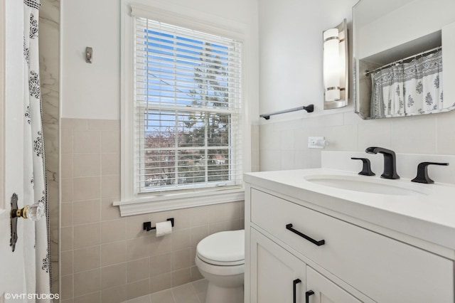 bathroom featuring vanity, tile walls, and toilet