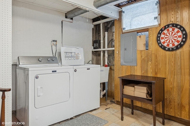 clothes washing area featuring separate washer and dryer, electric panel, and wood walls