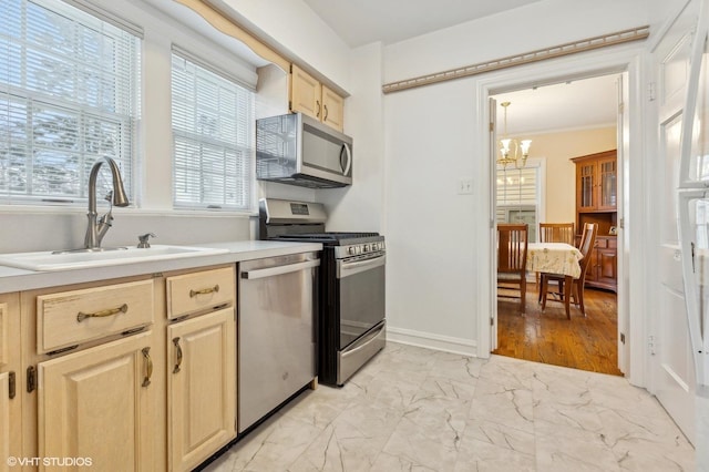 kitchen featuring pendant lighting, sink, stainless steel appliances, light brown cabinets, and an inviting chandelier