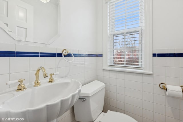 bathroom featuring toilet, sink, and tile walls