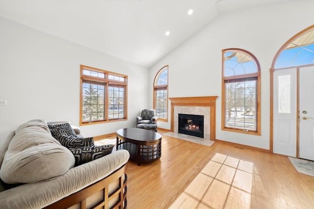 living room featuring high vaulted ceiling, light wood-type flooring, and a premium fireplace