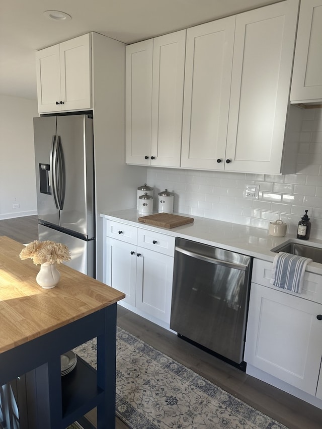 kitchen with dark wood-type flooring, white cabinetry, stainless steel appliances, backsplash, and butcher block countertops