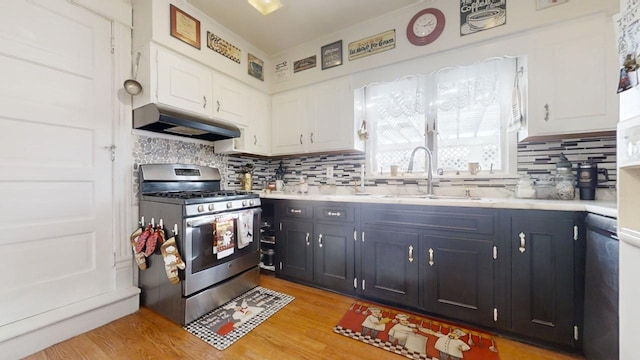 kitchen featuring decorative backsplash, stainless steel range with gas cooktop, white cabinetry, and sink