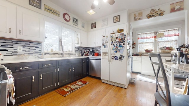 kitchen with light hardwood / wood-style flooring, sink, tasteful backsplash, white cabinetry, and stainless steel appliances