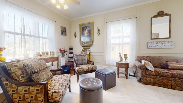 sitting room with ceiling fan, carpet, crown molding, and a healthy amount of sunlight