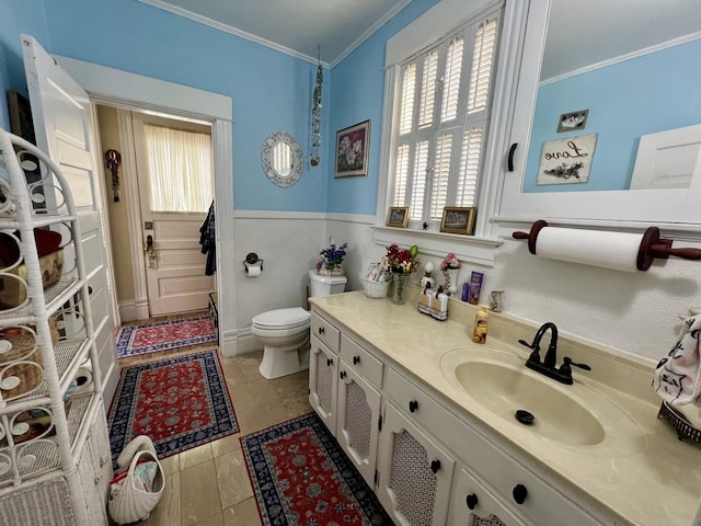 bathroom with toilet, vanity, crown molding, and tile patterned flooring