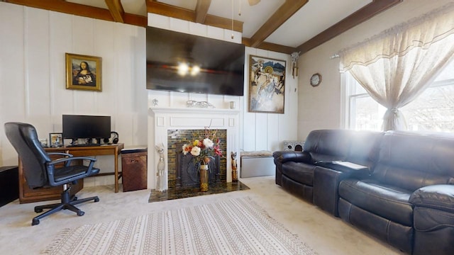 living room with a tile fireplace, beamed ceiling, and carpet