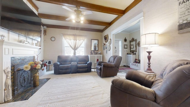 carpeted living room featuring ceiling fan, beamed ceiling, and a tile fireplace