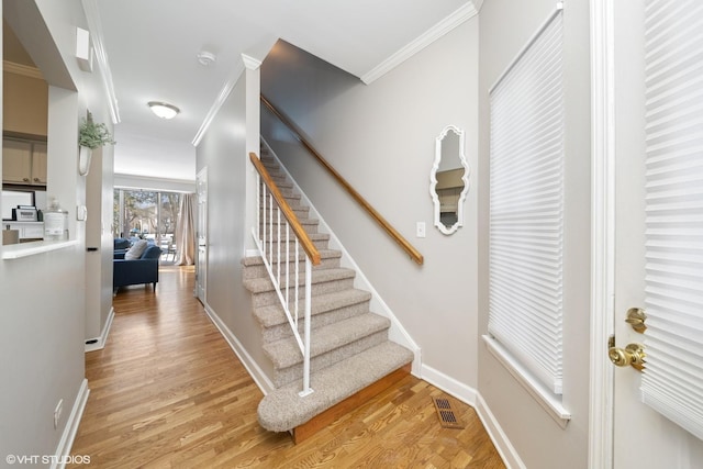 stairway featuring hardwood / wood-style floors and crown molding