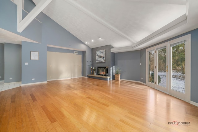 unfurnished living room featuring high vaulted ceiling, light wood-type flooring, and a fireplace