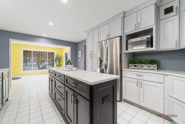 kitchen with light tile patterned flooring, appliances with stainless steel finishes, gray cabinetry, and a kitchen island