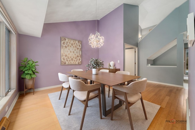 dining space featuring light hardwood / wood-style floors, an inviting chandelier, and vaulted ceiling