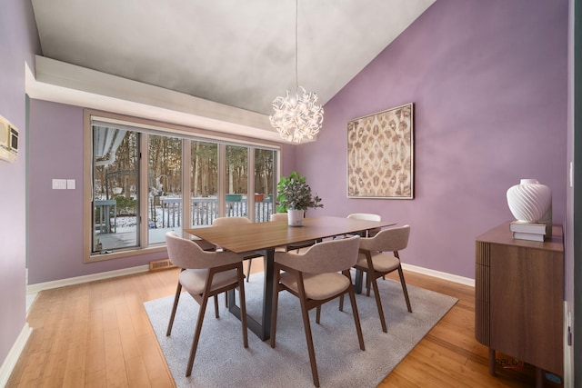 dining space with vaulted ceiling, a chandelier, and light hardwood / wood-style floors