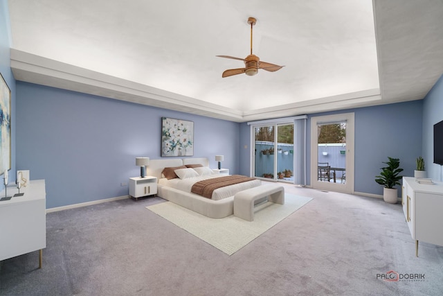 bedroom featuring ceiling fan, access to exterior, carpet flooring, and a tray ceiling